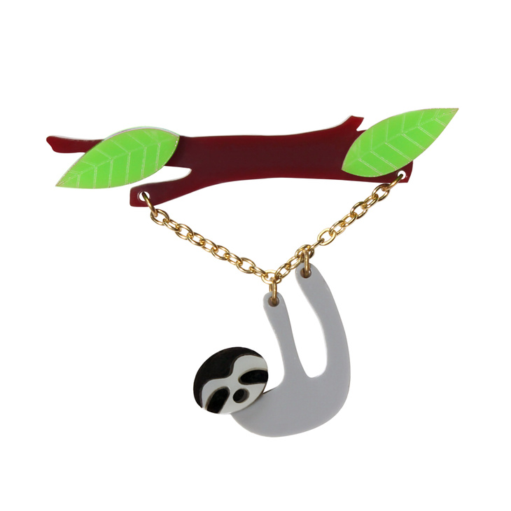 Laser cut acrylic brooch featuring a grey sloth hanging from a leafy branch